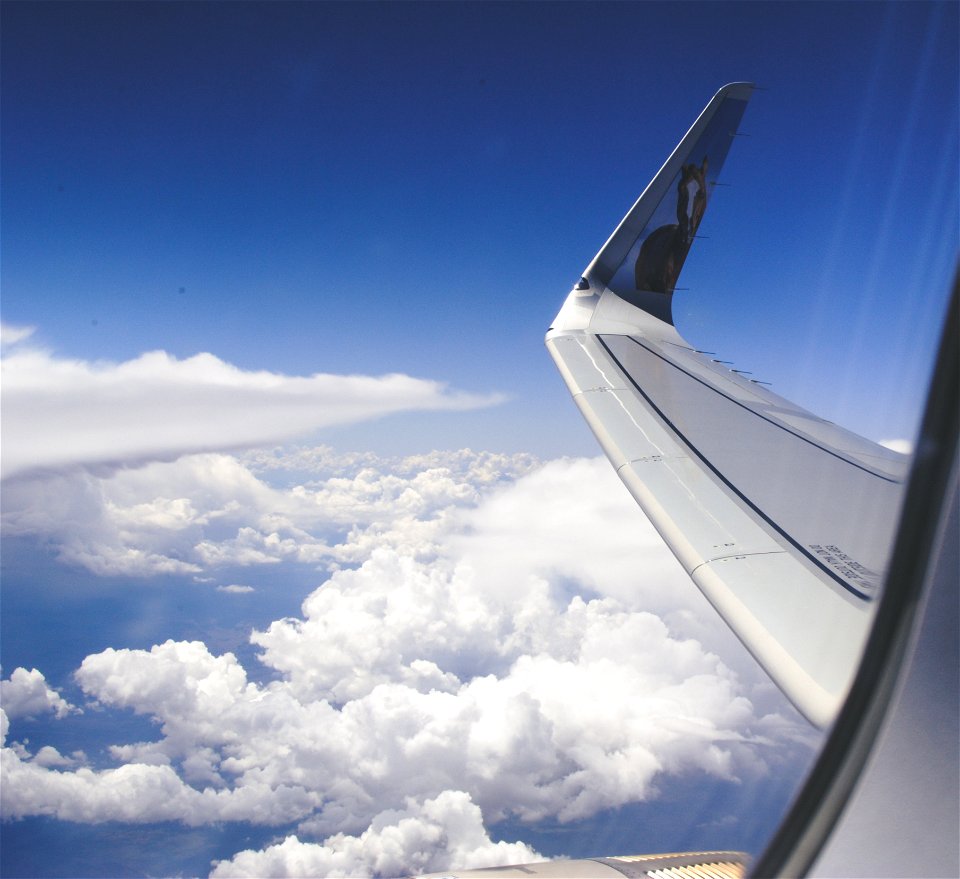 High-angle Photograph Of Airplane Wings Above The Clouds Under Clear Blue Sky