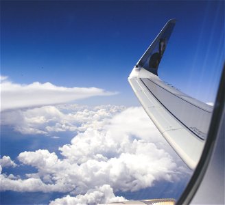 High-angle Photograph Of Airplane Wings Above The Clouds Under Clear Blue Sky photo