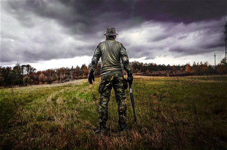 Man In Camouflage Suit Holding Shotgun photo