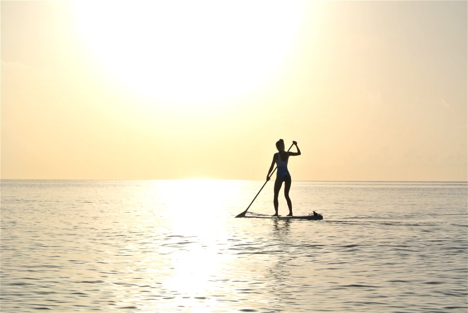 Woman Standing On Paddleboard On Body Of Water photo