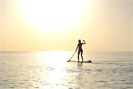 Woman Standing On Paddleboard On Body Of Water