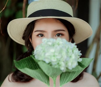 Woman Wearing White Hat Holding Flowers photo