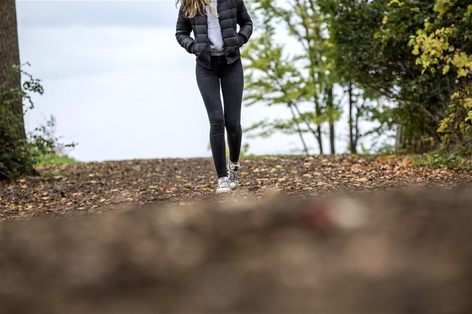 Woman In Black Leggings While Walking On Brown Road photo