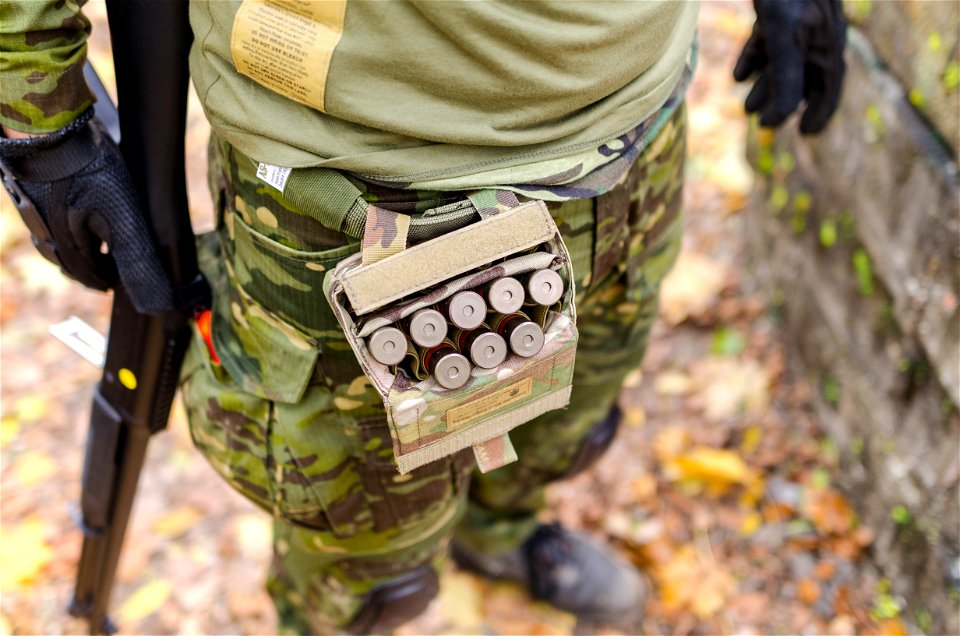 Person In Green Camouflage Print Pants Carrying Shotgun Shells photo