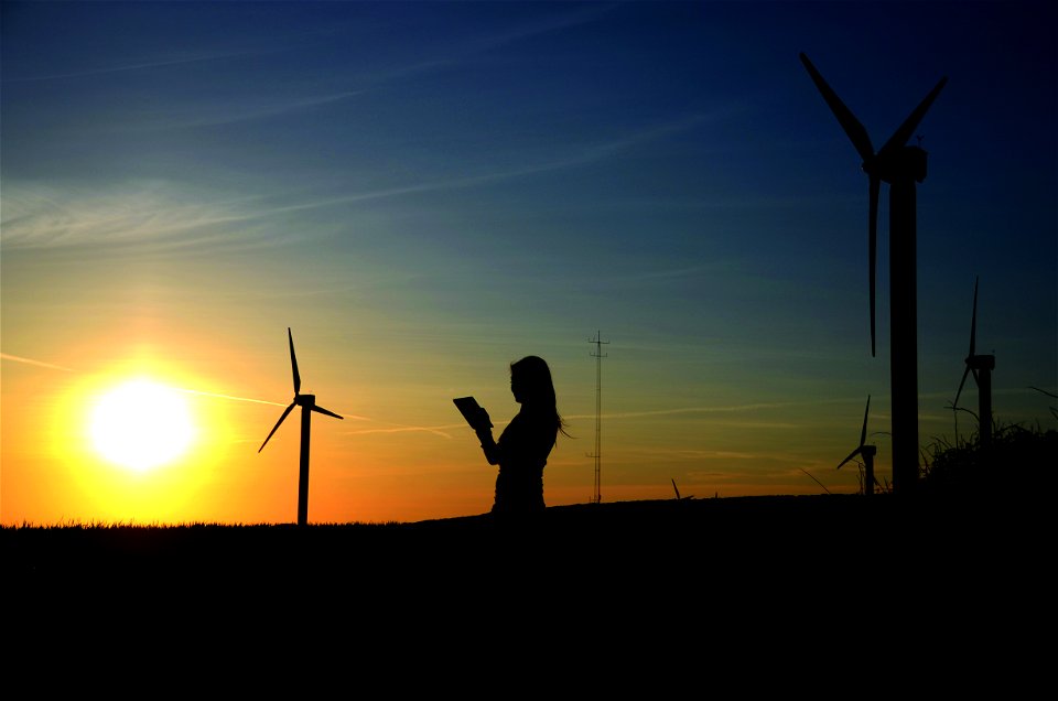 Silhouette Of Woman Holding Book Near Windmills photo