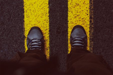 Person In Gray Sneakers Standing On Pedestrian Lane