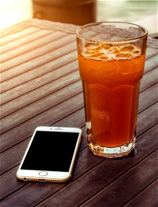 Orange Juice In Clear Drinking Glass Besides Gold Iphone 6 On Brown Wooden Table photo