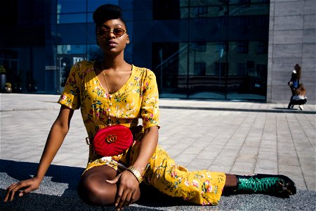 Woman In Yellow Floral Jumpsuit Sitting On Concrete Floor photo
