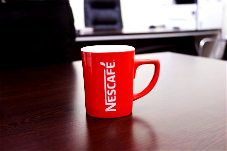 Red And White Nescafe-printed Mug On Brown Wooden Table photo