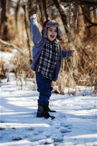 Boy In Gray Jacket And Blue Jeans Standing On Snow Outdoor photo