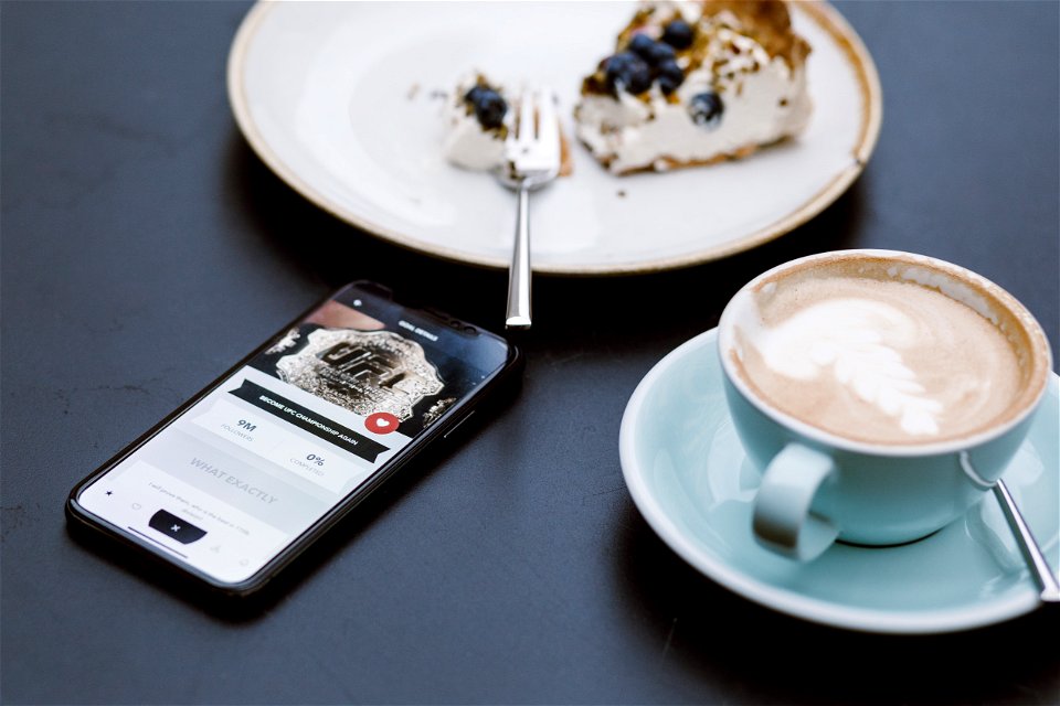 Black Smartphone Beside Coffee Mug In Shallow Focus Lens photo