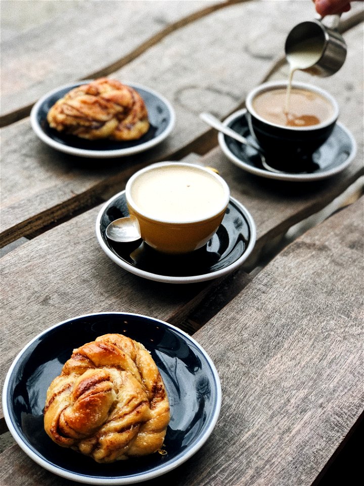 Two Brown And Black Ceramic Teacups Filled On Black Saucers photo