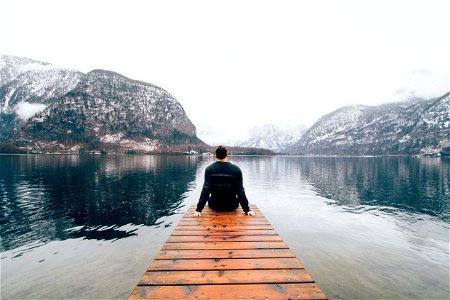 Man Seating In The Rail Way Near Body Of Water photo