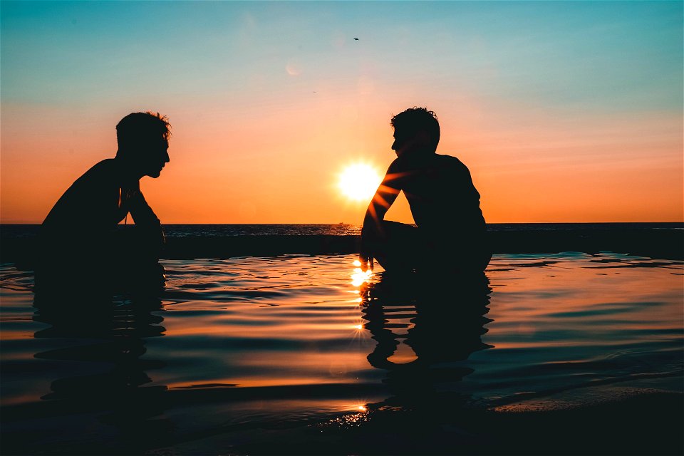 Photo Of Two Men On Seashore During Sunset