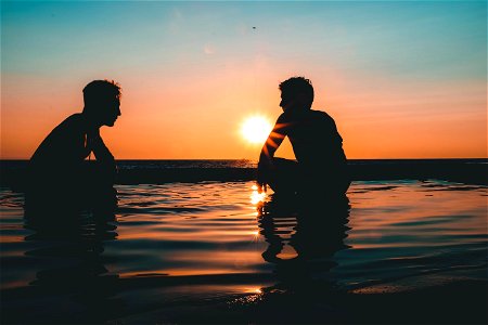 Photo Of Two Men On Seashore During Sunset photo