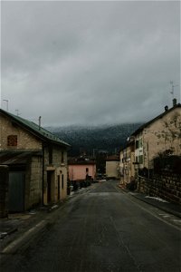 Gray Road Surrounded With Concrete Houses With Background Of Dark Clouds photo