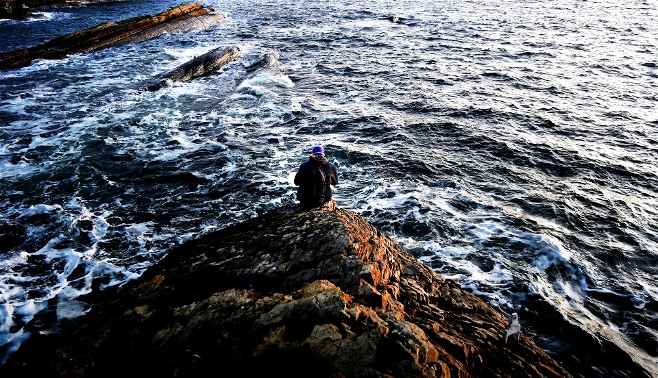 Photography Of Person Sitting On Rock Near Ocean photo