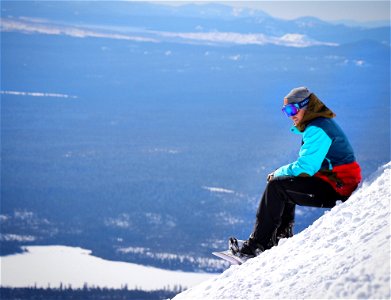 Person Wearing Blue And Red Winter Jacket Sitting On White Snow Mountain photo