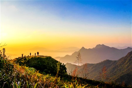 Photo Of People Standing On Top Of Mountain Near Grasses Facing Mountains During Golden Hours photo