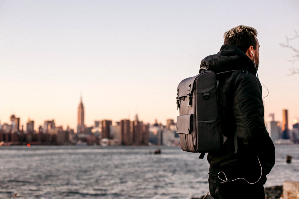 Man Wearing Black Bubble Jacket And Black Leather Backpack Near Bay
