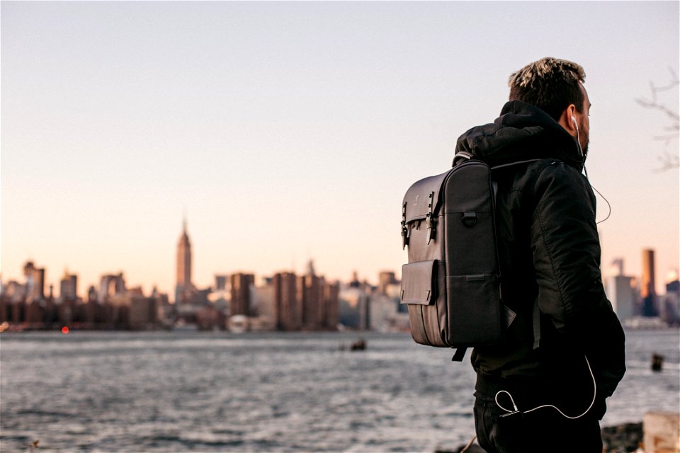 Man Wearing Black Bubble Jacket And Black Leather Backpack Near Bay photo