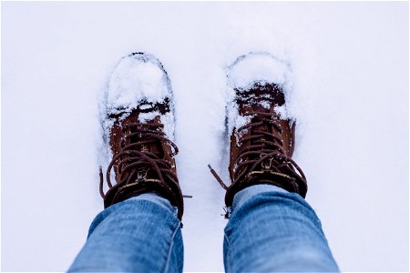 Person Wearing Brown Boots And Blue Denim Jeans Standing On Snow photo