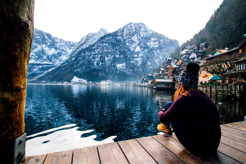 Woman In Purple Sweater Sitting On Wooden Floor With View Of Lake And Mountains photo