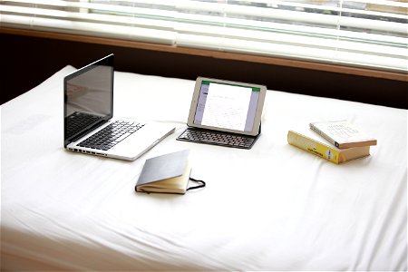Macbook Pro Over White Fabric Sheet Beside White Ipad photo