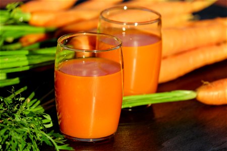 2 Clear Drinking Glass Container With Carrot Juice On Brown Wooden Tabletop In Tilt Shift Lens Photography photo