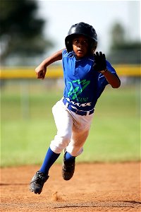 Boy In Blue And White Baseball Jersey Running On Brown Soil Field During Daytime photo
