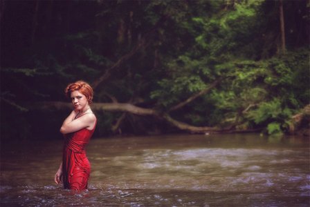 Woman In Red String Spaghetti Strap Dress On Body Of Water Near Forest photo
