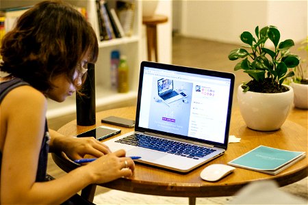 Woman In Black Tank Shirt Facing A Black Laptop Computer On Brown Wooden Round Table photo
