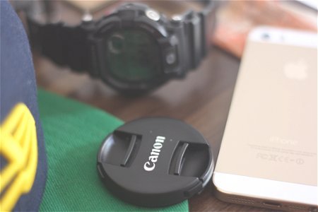 Canon Lens Cover Beside Gold Iphone 5s And Casio G Shock Chronograph Watch photo