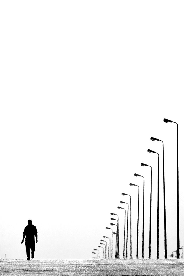 Man Walking Near Aligned Lamp Post photo