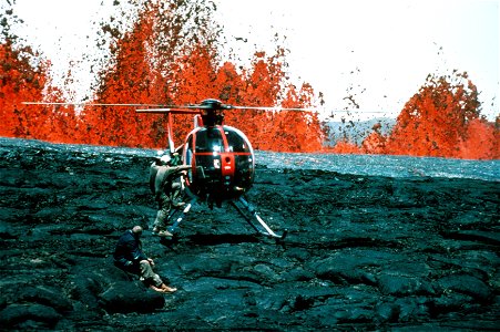 Several Hawaiian Volcano Observatory geologists board a helicopter as large lava fountains erupt in the background during the The 1984 eruption of Mauna Loa volcano in Hawaii. Helicopters provided acc