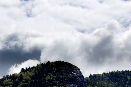 Thick Clouds Rising Behind Small Mountain photo