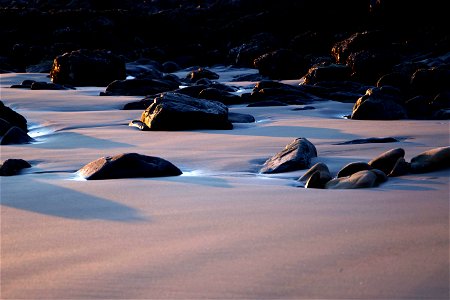 Shadowed Rocks on Smooth Sand Beach photo