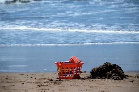 Sand Toys In Plastic Basket On Beach photo