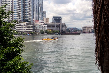 Boat Cruising Through Water Near Tall Buildings photo