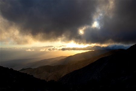 Sunset Behind Thick Clouds Above Mountains photo