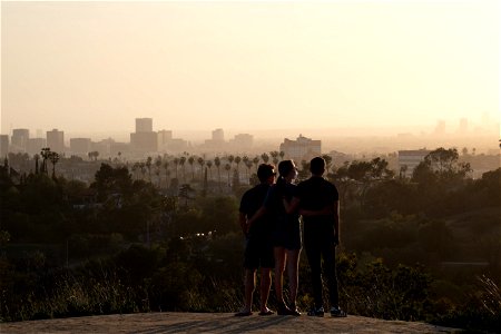 Three People Watching Sunset Beyond City Skyline photo