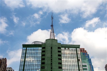 Radio Tower On Building Against White Clouds In Sky photo