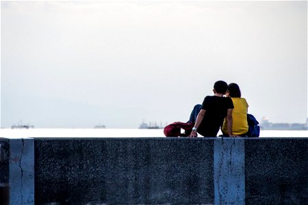 Two People Sitting On Seawall photo