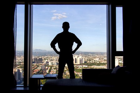 Man Standing In Front Of Window With City View photo