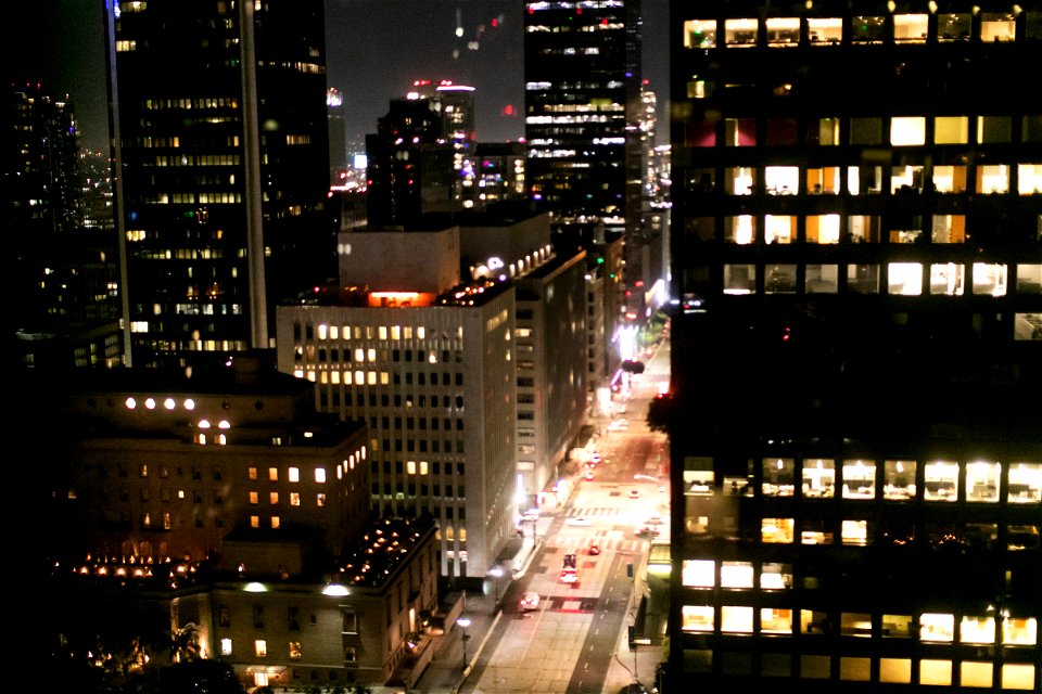 Brightly Illuminated Street Between Tall Buildings At Night photo