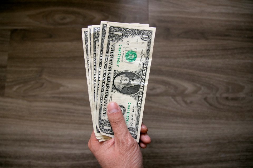 One Us Dollar Bills In Left Hand