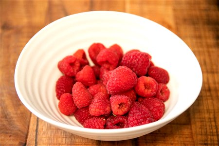 Raspberries In White Bowl On Wood photo
