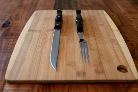 Steak Knife And Fork On Wood Chopping Board photo
