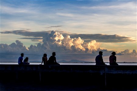 People Sitting On Coastal Ledge During Sunset photo