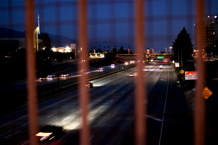 Traffic Through Blurry Wire Mesh Fence At Night photo